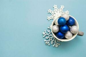 bleu et argent Noël des balles dans une tasse sur une bleu Contexte. Créatif concept de Noël et Nouveau an. photo