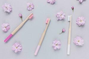 Trois Naturel en bois bambou brosses à dents sur rose floral Contexte photo