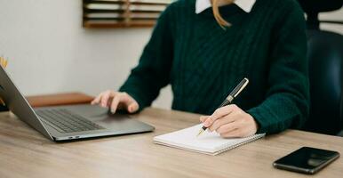 main de femme d'affaires travaillant avec un nouvel ordinateur moderne et écrivant sur le diagramme de stratégie du bloc-notes comme concept lumière du matin photo