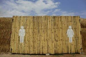 Contexte conception de bambou clôture avec blanc toilettes salle de repos La peinture symboles homme et femme. signe icône Masculin et femelle toilettes. photo