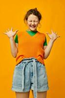 portrait de une Jeune fille dans un Orange chandail denim short photo