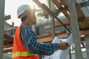 inspecteur ou ingénieur est inspecter construction et qualité assurance Nouveau maison en utilisant une bleu imprimer. ingénieur ou architectes ou contacteur travail à construire le maison avant remise il plus de à le propriétaire photo