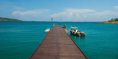 paysage été passerelle pont marcher mer et aussi petit port. et petit bateau amarré avec vue de bleu mer, clair ciel faire le ménage, adapté vacances Voyage à golfe Thaïlande Khao apprendre toi nationale parc rayong photo