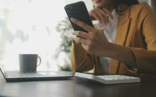 portrait d'une jeune femme asiatique pigiste à la main travaille son travail sur une tablette informatique dans un bureau moderne. faire un rapport d'analyse comptable sur les données d'investissement immobilier, le concept de systèmes financiers et fiscaux. photo