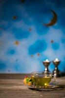 thé dans une verre tasse avec arabe bonbons sur une en bois surface. photo