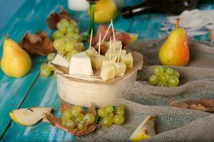 fromage tranches, poire, et les raisins sur une en bois rester. photo