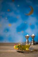 thé dans une verre tasse avec arabe bonbons sur une en bois surface. photo