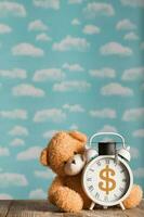 américain dollar signe représenté sur une ancien l'horloge avec académique casquette. marron peluche nounours ours dans le Contexte. photo