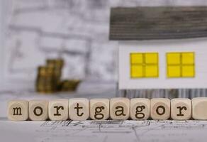 mot débiteur hypothécaire composé de en bois lettre. petit papier maison dans le Contexte. photo