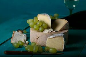 fromage, les raisins et du vin sur en bois cyan surface. photo