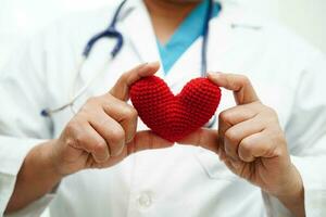 femme médecin asiatique tenant un coeur rouge pour la santé à l'hôpital. photo