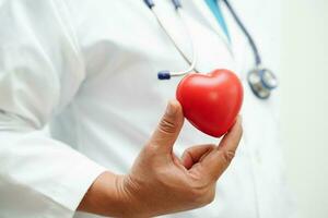 femme médecin asiatique tenant un coeur rouge pour la santé à l'hôpital. photo