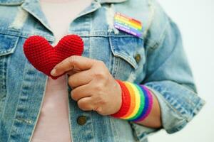 asiatique femme en portant rouge cœur avec arc en ciel drapeau, lgbt symbole droits et le sexe égalité, lgbt fierté mois dans juin. photo