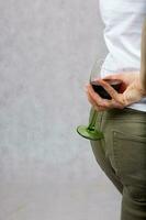 Jeune Dame habillé dans jeans garde une verre de rouge du vin. fermer photo