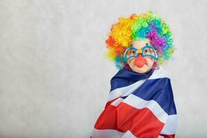 garçon habillé dans le costume de une pitre couvert lui-même avec Britanique drapeau. photo