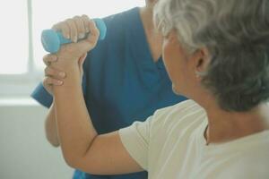 physiothérapeute homme donnant exercice avec haltère traitement à propos bras et épaule de athlète Masculin patient physique thérapie concept photo