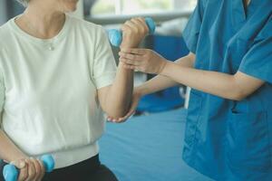 physiothérapeute homme donnant exercice avec haltère traitement à propos bras et épaule de athlète Masculin patient physique thérapie concept photo