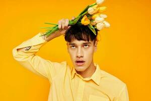 jolie homme dans Jaune des lunettes avec une bouquet de fleurs Jaune Contexte inchangé photo