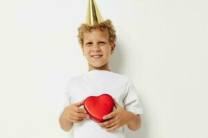 de bonne humeur garçon avec une casquette sur le sien tête une cadeau boîte dans le forme de une cœur photo