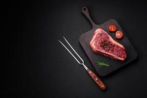 Frais juteux brut Nouveau york du boeuf steak avec sel, épices et herbes photo