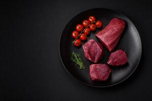 juteux brut du boeuf avec épices, sel et herbes sur une foncé béton Contexte photo