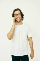 Beau homme dans une blanc T-shirt la communication par téléphone isolé Contexte photo