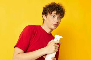 Jeune aux cheveux bouclés homme dans une rouge T-shirt détergents dans mains posant monochrome coup photo