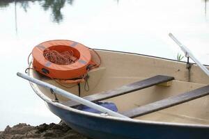 rivière bateau avec rames et un Orange la vie bague sur le l'eau. photo