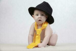 souriant enfant dans une rétro chapeau et attacher sur une blanc Contexte. marrant six mois vieux bébé dans élégant vêtements. photo