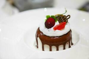 sur une blanc plaque, une petit gâteau arrosé avec Chocolat glaçage et décoré avec baies. photo