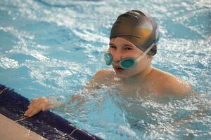 garçon dans une nager casquette et nager des lunettes de protection dans le bassin. le enfant est engagé dans le nager section. photo