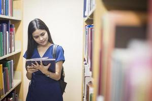 Jolie femme asiatique étudiant un livre de lecture dans la bibliothèque photo