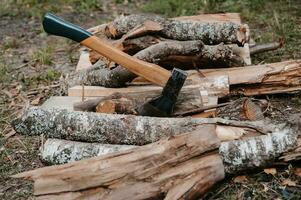 un vieux battu hache est coincé dans une Journal sur une pile de bois de chauffage. Extérieur des loisirs. préparation pour le feu. photo