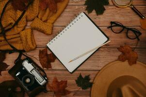 l'automne accessoires, mise à plat. chapeau, chandail, feuilles érable, lunettes, bloc-notes, rétro caméra sur en bois Contexte. copier espace photo