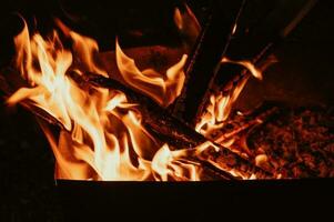 une feu dans fermer, flammes, carbonisé pièces de journaux et cendres dans le ouvert air. camping. photo