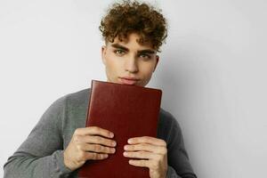 mignonne gars avec frisé cheveux avec une livre dans le sien mains formation photo