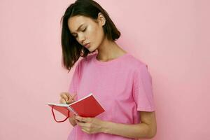 optimiste Jeune femme dans une rose T-shirt rouge carnet et stylo rose Contexte photo