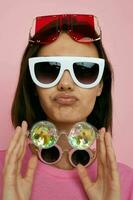 optimiste Jeune femme une lot de des lunettes sur le visage dans une rose T-shirt isolé Contexte photo