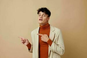 portrait de une Jeune homme posant avec une téléphone dans le sien mains dans une veste élégant style lumière Contexte inchangé photo