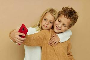 peu garçon et fille avec une rouge téléphone ensemble les technologies isolé Contexte photo