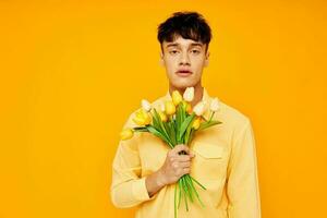 Beau gars dans Jaune des lunettes avec une bouquet de fleurs Jaune Contexte inchangé photo