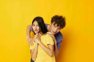 portrait de une homme et une femme dans coloré t-shirts posant relation amicale amusement Jaune Contexte inchangé photo