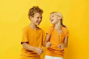 mignonne élégant des gamins dans Jaune t-shirts permanent côté par côté enfance émotions isolé Contexte inchangé photo