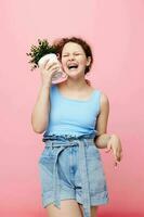 portrait de une Jeune femme dans une bleu T-shirt et short une pot de fleur isolé arrière-plans inchangé photo