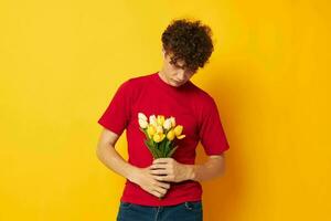 Jeune aux cheveux bouclés homme dans une rouge T-shirt une bouquet de fleurs vacances cadeau mode de vie inchangé photo