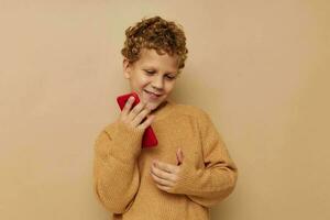 de bonne humeur garçon avec rouge téléphone dans mains posant beige Contexte photo