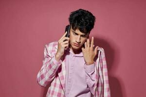 Beau gars avec une téléphone dans main rose blazer mode élégant style modèle studio photo