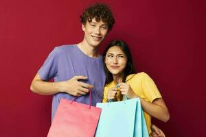 mignonne Jeune couple dans coloré t-shirts avec Sacs achats isolé Contexte inchangé photo