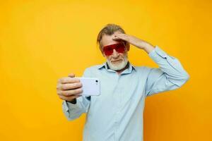 photo de retraité vieux homme bleu chemises avec des lunettes prend une selfie isolé Contexte