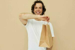 Beau homme dans une blanc T-shirt avec papier sac isolé Contexte photo